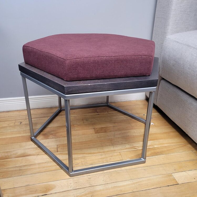 small ottoman with burgundy fabric top, and silver metal base.