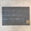 Woven vinyl placemat in black. Mix of weaves creates four horizontal stripes of varying heights.