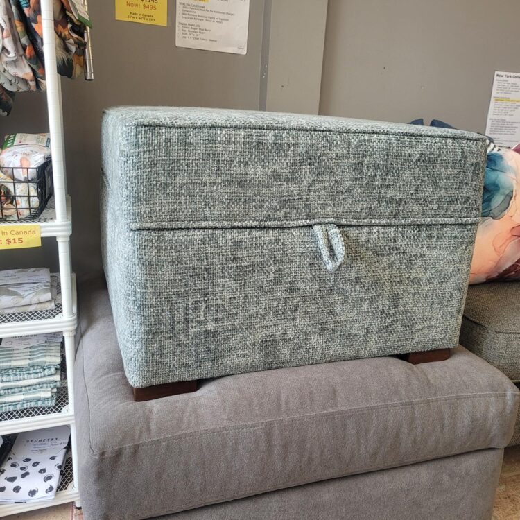 Square ottoman in medium blue textured fabric.